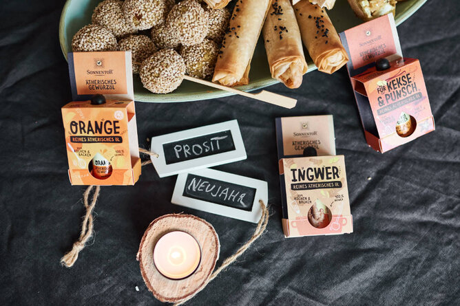 Auf dem Foto sind verschiedene Snacks zu sehen. Daneben sieht man auch ätherische Gewürzöle von SONNENTOR. | © SONNENTOR