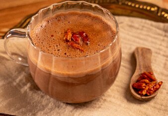 Gewürz Kakao mit Chili in einer Glastasse mit einer Vanilleschote als Dekoration! | © SONNENTOR